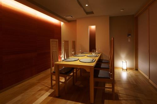 a dining room with a table with chairs and wine glasses at Aburaya Tousen in Yamanouchi