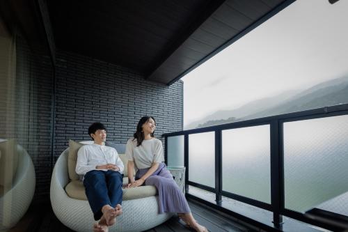 a man and a woman sitting on a couch on a balcony at Aburaya Tousen in Yamanouchi