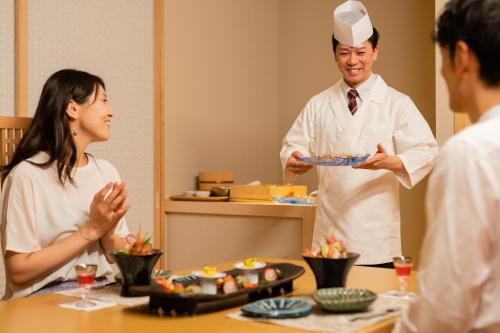 a man holding a plate of food next to a woman at Aburaya Tousen in Yamanouchi