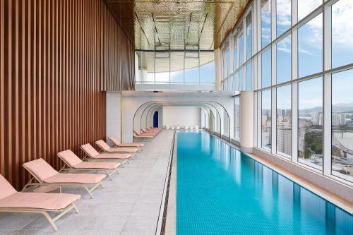 a swimming pool in a building with chairs and windows at Naru Ambassador Hotel Seoul - MGallery Collection in Seoul