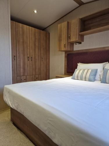 チャペル・セント・レオナルズにあるCosy caravans Meadow viewのベッドルーム1室(白い大型ベッド1台、木製キャビネット付)