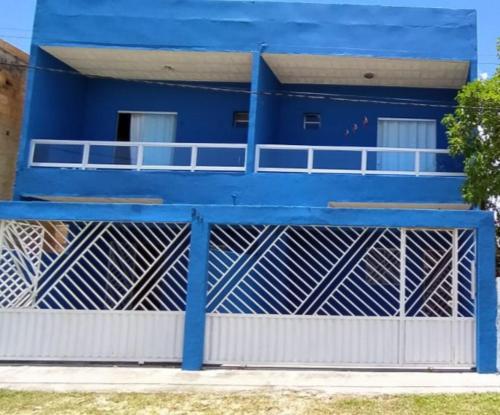 a blue house with a white fence in front of it at Residencial Praia Quente casas in Nova Viçosa