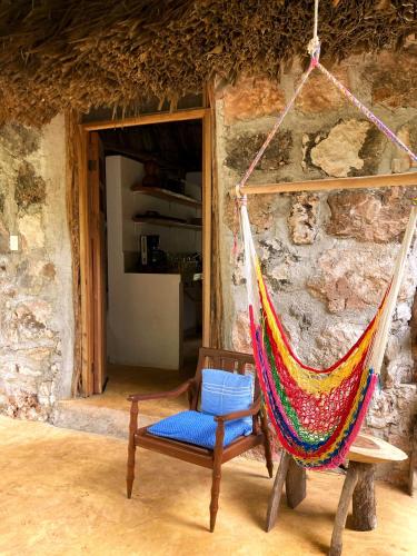 a hammock in a room with a stone wall at Encantadora Villa Maya tradicional en Rancho Agroecologico in Tzucaceb