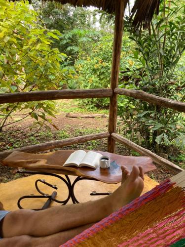 a person with their feet on a table with a book at Encantadora Villa Maya tradicional en Rancho Agroecologico in Tzucaceb