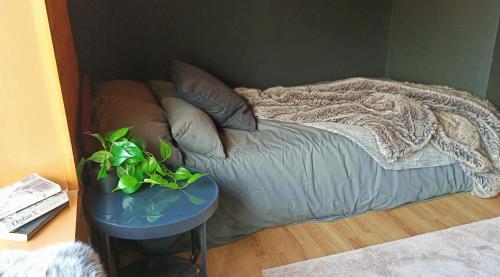 a bed with a blanket and a table with a plant at Hooting Owl private ski chalet in Niseko