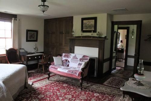 a bedroom with a bed and a chair and a fireplace at Upstairs Historic 1 Bedroom 1 Bath Suite with Mini-Kitchen, Porch & River Views in Elkins