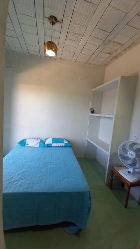 a bedroom with a blue bed and a table at Residencial Praia Quente casas in Nova Viçosa