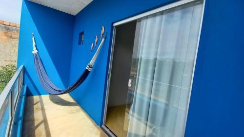 a balcony with a blue wall and a glass door at Residencial Praia Quente casas in Nova Viçosa