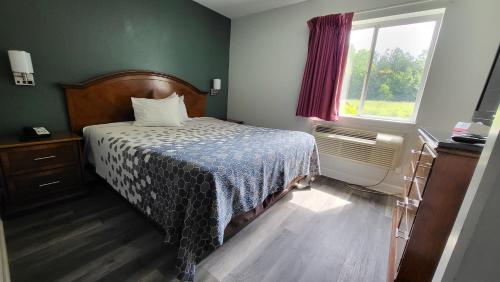 a small bedroom with a bed and a window at Stonewood Inn & Suites of Carrollton - Smithfield in Carrollton