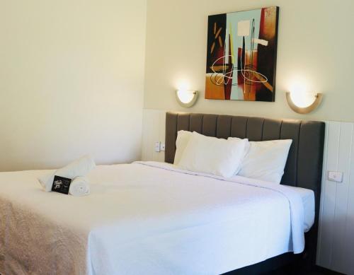 a bedroom with a large bed with white sheets at Chinchilla Great Western Motor Inn in Chinchilla