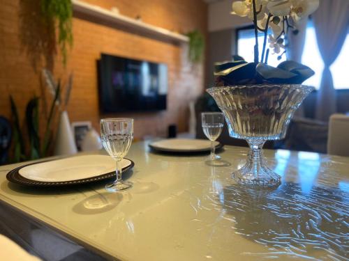 a table with glasses and plates and a vase on it at QUARTO/SALA COM VISTA P/ O MAR DE PAJUÇARA in Maceió