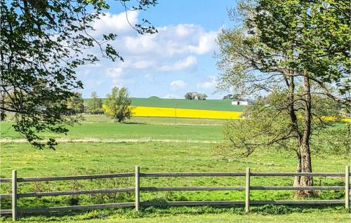 a wooden fence in a field with a tree at Lovely Home In Skivarp With Wifi in Skivarp