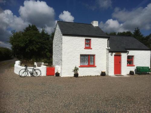 a white house with a bike parked in front of it at Cobblers Cottage Creggan in Greencastle