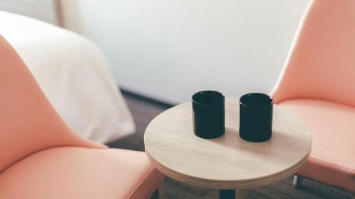 two black cups sitting on a table next to two orange chairs at Kuretake Inn Premium Nagoya Nayabashi in Nagoya