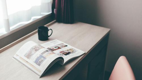 a book on a table with a cup and a mug at Kuretake Inn Premium Nagoya Nayabashi in Nagoya