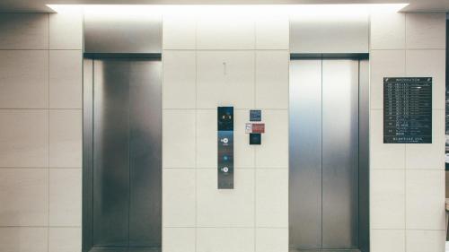 two elevators in a building with a sign on the wall at Kuretake Inn Premium Nagoya Nayabashi in Nagoya
