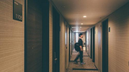 a man walking down a hallway in a building at Kuretake Inn Premium Nagoya Nayabashi in Nagoya