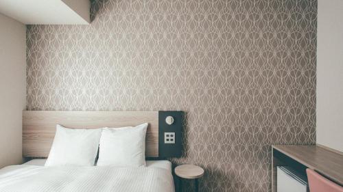 a bedroom with a bed and a brown wall at Kuretake Inn Premium Nagoya Nayabashi in Nagoya