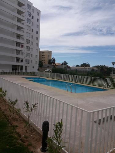 a swimming pool with a white fence next to a building at La Serena vista al mar in La Serena