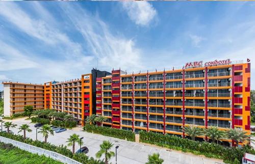 an apartment building with red and orange windows and palm trees at Квартира in Ban Bo Sai Klang