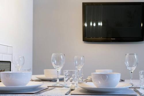 a table with plates and wine glasses and a television at No6 - Beverley - Elegant Townhouse - Central location in Beverley