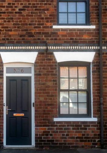a brick building with a black door and two windows at No6 - Beverley - Elegant Townhouse - Central location in Beverley