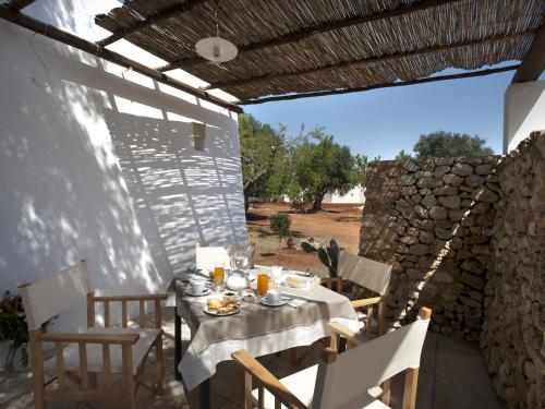 a table and chairs on a patio with a stone wall at I Mulicchi in Specchia