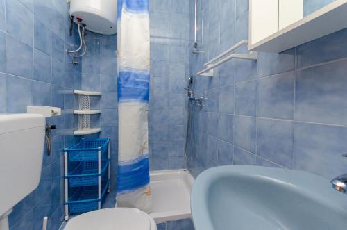 a blue tiled bathroom with a toilet and a sink at Apartments Ljubica J in Lopar