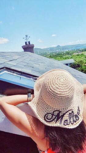 a woman wearing a straw hat sitting on a roof at 墾丁勿忘我城堡莊園 in Hengchun