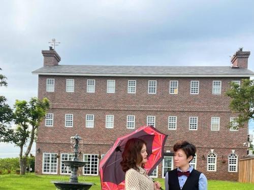two women are standing in front of a building with an umbrella at 墾丁勿忘我城堡莊園 in Hengchun