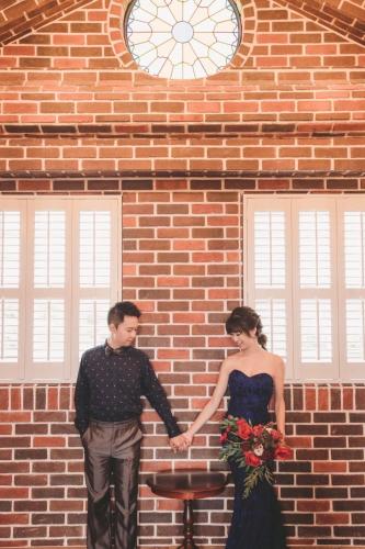 a bride and groom holding hands in front of a brick building at 墾丁勿忘我城堡莊園 in Hengchun