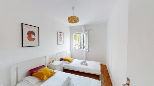 biały pokój z 2 łóżkami i oknem w obiekcie Live Like a Local Stylish 2BR with Balcony & Parking w mieście Saint-Denis