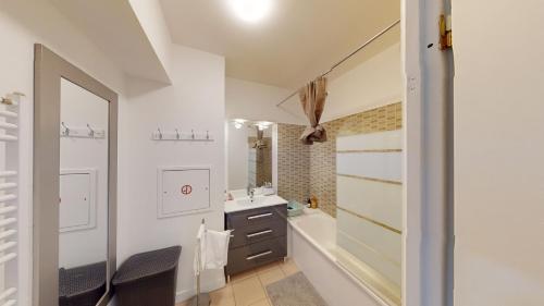 a bathroom with a tub and a sink and a mirror at Live Like a Local Stylish 2BR with Balcony & Parking in Saint-Denis