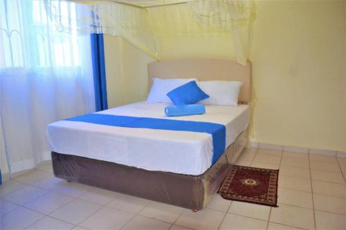 a bedroom with a bed with blue and white pillows at Mtwapa HomeStay 3br Apartments in Mombasa