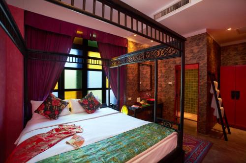 a bedroom with a canopy bed with red curtains at Shanghai Mansion Bangkok in Bangkok