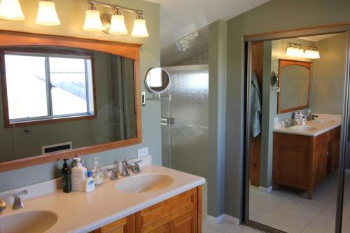 uma casa de banho com 2 lavatórios, um espelho e um chuveiro em Joshua Tree’s Highland Hideaway Compound em Joshua Tree
