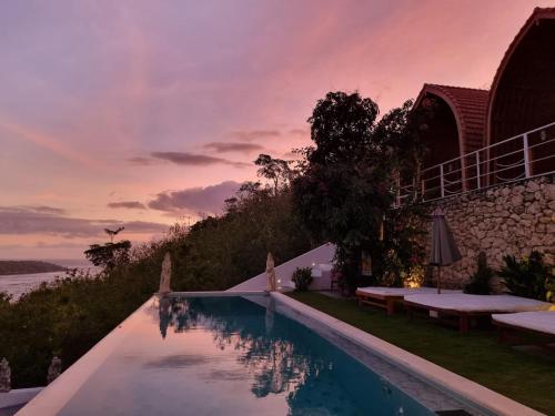 a pool with a view of the ocean at sunset at Butterfly Villas Nusa Ceningan in Nusa Lembongan
