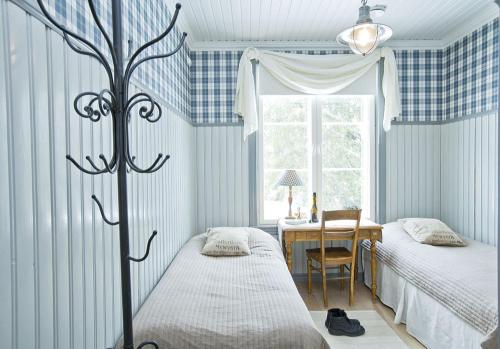 a bedroom with two beds and a table with a window at Westerby Gård in Inkoo