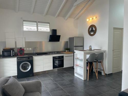 a kitchen with a stove and a sink and a table at Charmante maison avec Jaccuzi et piscine Sunrise beautiful house with Jaccuzi and swimming pool in Lamentin