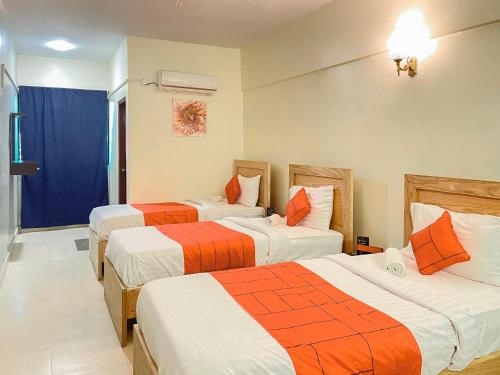 Habitación de hotel con 2 camas en naranja y blanco en GOHO Rooms 10th Commercial, en Karachi