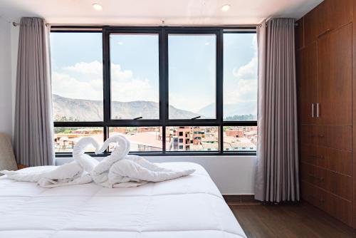 two swans are sitting on a bed in front of a window at Town Center Apartments in Urubamba