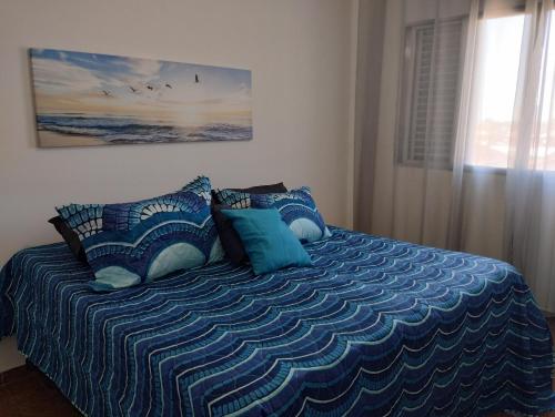 Un dormitorio con una cama con almohadas azules y una ventana en Apto da Li na Praia Grande I, en Praia Grande