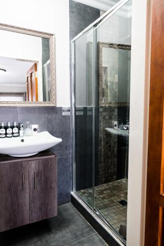 a bathroom with a glass shower and a sink at Villa Gracia Guesthouse in Klerksdorp