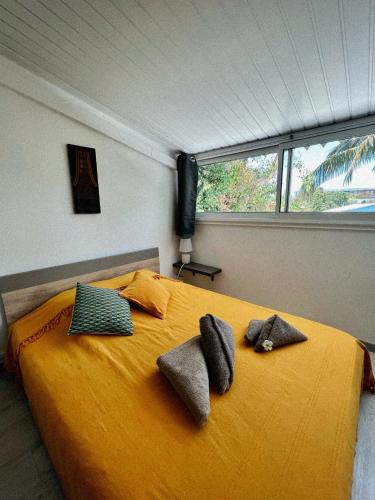 a bedroom with a yellow bed with towels on it at Villa Kazabona Saint-Pierre centre - Chambres d'hôte in Saint-Pierre