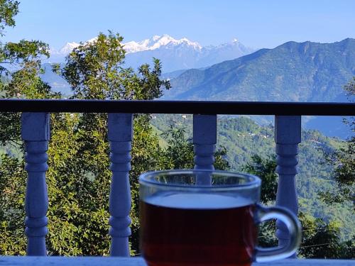 a cup of coffee on a balcony with mountains in the background at Nature Love Homestay By StayApart in Takdāh