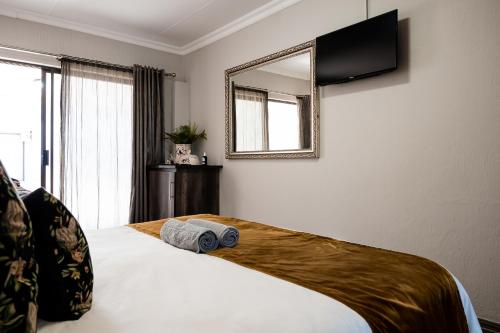 a bedroom with a bed with a mirror on the wall at Villa Gracia Guesthouse in Klerksdorp