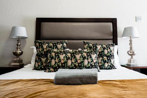 a bed with a pillow on it with two lamps at Villa Gracia Guesthouse in Klerksdorp
