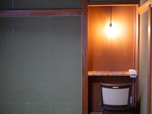 a room with a table and a chair and a light at Hostel Murasaki in Takayama