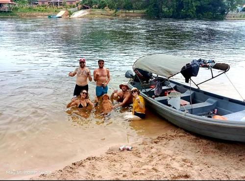 a group of people standing in the water next to a boat at The Hideaway in Kampot