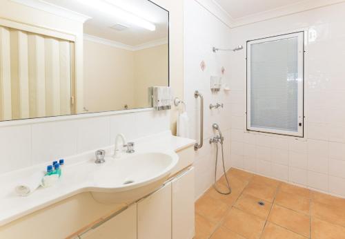 ein weißes Badezimmer mit einem Waschbecken und einem Spiegel in der Unterkunft Sails On Horseshoe in Horseshoe Bay